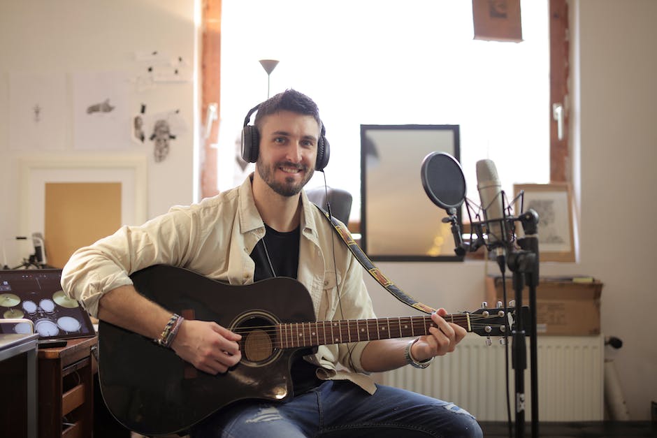 Image description: A person wearing headphones, holding a microphone, and sitting in a recording studio.