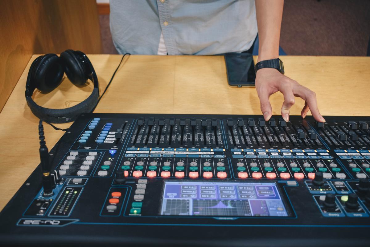 An image displaying a person adjusting knobs on a sound mixing console.